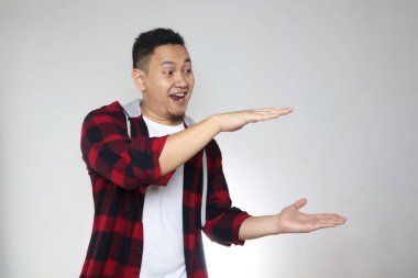 Elleri arasında bir şey gösteren mutlu genç Asyalı adam, beyaz arka planda fotokopi alanı olan ürün pazarlama reklam konsepti