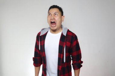 Genç Asyalı adam öfkeden bağırıyor. Öfke saldırganlığı kavramı. Beyaz arka plan, çılgın hüsran.