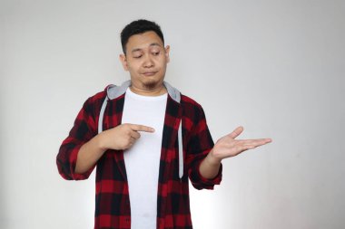 Genç Asyalı adam boş elle bir şey gösteriyor, gülümsüyor. Vücut portresini kapat