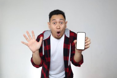 Genç Asyalı bir adamın portresi akıllı telefon modelini mutlu ve şok edici bir ifadeyle sunuyor.