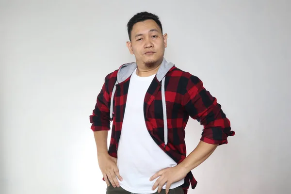 Portrait of funny young cocky Asian man shows his over confidence, hands on hips with arrogant gesture, over white