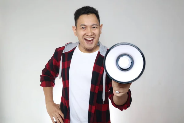 Young Asian man making announcement, marketing advertisement concept, Smiling expression using megaphone, over white background