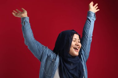 Kırmızı tesettürlü komik bir Asyalı müslüman kadının portresi. Mutlu bir şekilde dans ediyor. İyi haberi kutluyor, zaferi kutluyor.