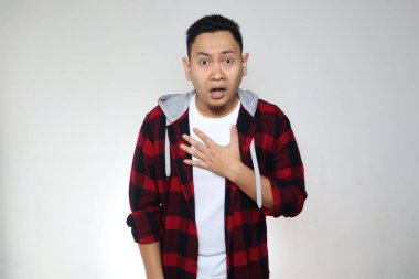 Genç Asyalı şok olmuş bir jest gördüğü şeye inanamıyor. Endişeli ifade, beyaz arkaplan üzerinde