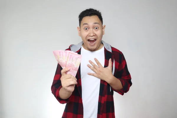 幸せな若いインドネシア人男性の肖像ルピアお金を保持し 笑って勝利のジェスチャーを笑って 白い背景に — ストック写真