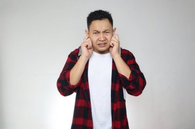 Genç Asyalı adam kulaklarını kapatıyor. Kötü haber duymak ya da duymaktan kaçınıyor. Zihinsel baskı altında stres.