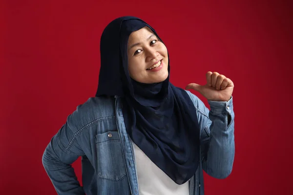 有自信的穆斯林女子的画像 头戴头巾 面带微笑 在红色背景下指着自己 — 图库照片