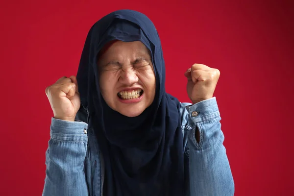 ヒジャーブを身に着けているアジアのイスラム教徒の女性の肖像は 赤を背景に 怒って叫んでジェスチャーを示しています — ストック写真