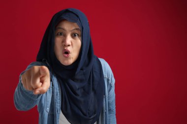 Başörtüsü takmış kızgın müslüman kadın portresi kameraya tehdit edici hareketlerle bakıyor, deli patron seni işaret ediyor.