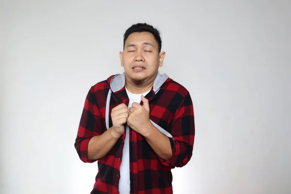 Young Asian man gets cold and fever, feeling deezy and shiver, against grey background