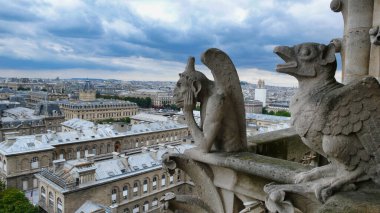 Notre Dame 'ın Paris' e tepeden bakan Gargoyles 'ı: Notre Dame Katedrali' nin ikonik heykelleri dramatik ve bulutlu bir günde Paris şehir manzarasına bakıyorlar..