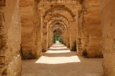 Bir Fas Kasbası 'ndaki eski harabe kemerler - Fas' taki eski bir kasbanın veya antik bir kalenin açık ahşap kapısından görünen bir manzara.