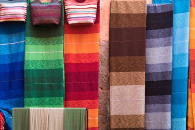 Çarşıda renkli çizgili kumaşlar, Fas 'ta bir markette asılı duran iki çanta da dahil olmak üzere renkli çizgili kumaşların yakın çekimi..