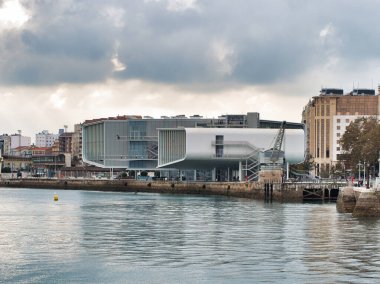 Yeşil Şehir Parkı ve Modern Mimari - Önünde yeşil çimenler ve ağaçlar olan sakin bir park, bulutlu bir günde modern, cam panelli bir binaya götürüyor..