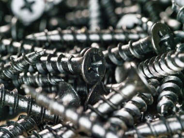 Siyah alçıpanının makro görünümü arka plan vidaları - siyah alçıpan yığınının detaylı, yakın görüntüsü, desenli ve endüstriyel bir arkaplan oluşturur.