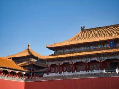 Pekin 'in Yasak Şehri' nin göz kamaştırıcı çatıları ve duvarları, açık mavi gökyüzüne karşı altın güneş ışığıyla yıkanmış, Çin İmparatorluğu mimarisinin ihtişamını gösteriyor..