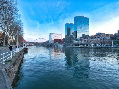 Bulutlu bir günde Bilbao şehir manzarası yansıması. Bilbao 'nun modern ufuk çizgisi, kuleleri ve binaları Nervin Nehri' nin sakin yüzeyine yansıyor bulutlu, dramatik bir gökyüzünün altında.