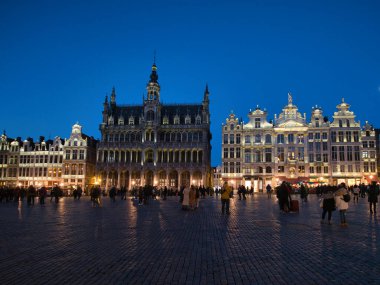 Full moon over Brussels historic buildings - A night view of the illuminated facade of a historic building in Brussels' Grand-Place, with a full moon glowing in the dark blue sky.