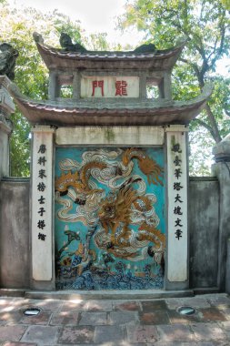 Altın bir ejderhanın canlı duvar duvar resmi, renkli seramik bir kabartmanın tam kare görüntüsü, altın bir ejderhayı açık mavi bir arkaplan ve Çin karakterleri ile bulut motifleri ile destekliyor..