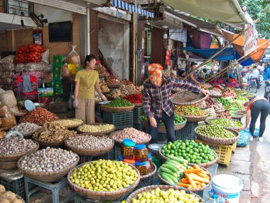 Canlı ve hareketli meyve ve sebze pazarı - Vietnam 'da satıcı ve müşterilerle dolu, sepetler dolusu taze meyve ve sebze sergilenen canlı bir sokak pazarı.