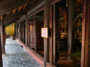 Vietnam 'daki Budist tapınağı. Koyu ahşap sütunları, süslemeleri ve fayanslı zemini olan bir Budist tapınağının içi. Huzurlu ve ruhani bir atmosfer yaratıyor..