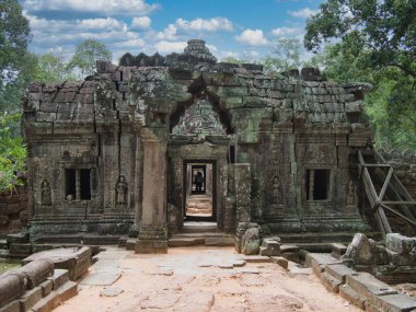 Angkor Tapınağı Kapısı - Angkor 'da yıpranmış bir tapınak kapısı, sık ormanlarla çevrili, antik ve gizemli yapıya açılan bir geçit gösteriyor.