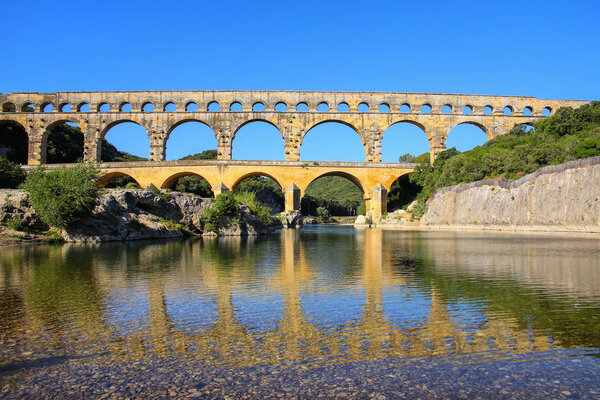 Aqueduct Pont du Gard reflected in Gardon River, southern France. It is the highest of all elevated Roman aqueducts.