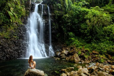 Genç kadın bikini tarafından orta Tavoro şelaleler Taveuni Island, Fiji Bouma Ulusal Miras Park'ta oturuyor. Taveuni Fiji'de üçüncü büyük adasıdır.