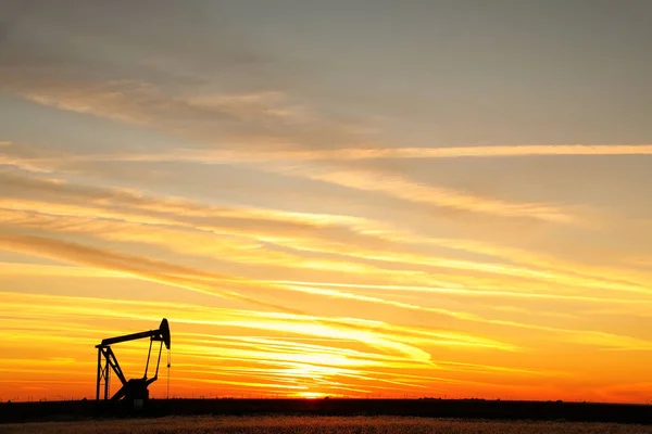 Pumpenheber im Ölfeld bei Sonnenuntergang — Stockfoto