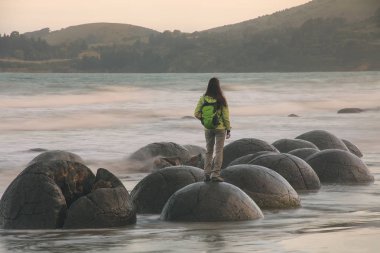 Koekohe Plajı'nda Moeraki Boulder üzerinde duran kadın, Otago, Güney