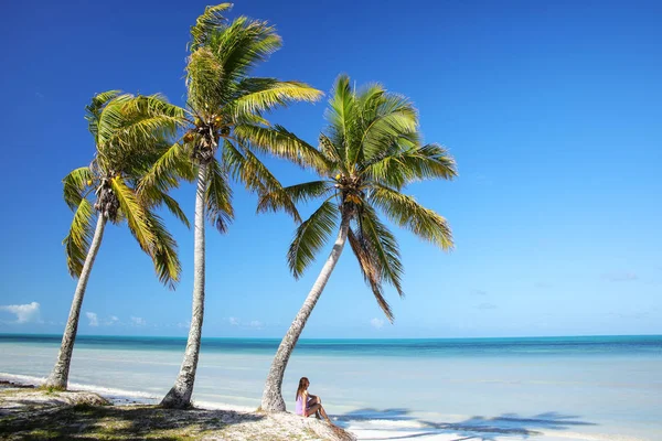 Kvinnan sitter vid palmerna på kusten av Ouvea lagun på — Stockfoto