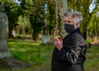 Mezarlık maskeli yaşlı kadın.