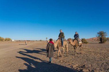 Merzouga, Fas - 29 Aralık 2017: Merzouga köyü yakınlarındaki Sahra çölünde deveye binen turistler.