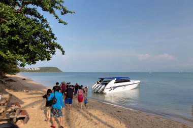 İnsanlar sahilden tekneye yürüyorlar.