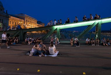 Budapeşte, Macaristan - 6 Temmuz 2019: Macar başkentinin en eski köprülerinden biri olan Liberty Köprüsü 'nde yaz gecesinin tadını çıkaran tanımlanamayan insanlar. Köprü hafta sonları ulaşıma kapatıldı.
