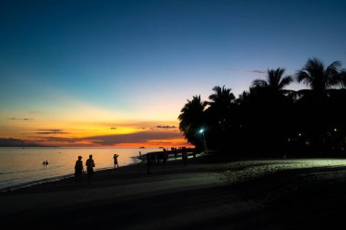 Gün batımında sahilde bir çiftin silueti.