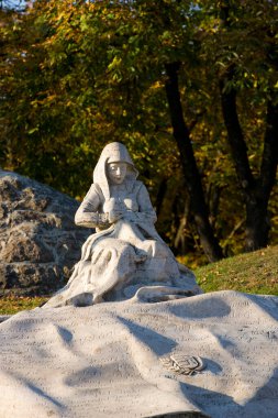 Taş bahçedeki genç bir kadının heykeli.