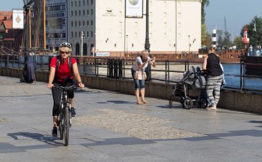 GDANSK, POLAND - 19 Eylül 2015: Kimliği belirsiz insanlar Gdansk 'ın merkezinde bisiklet sürüyor. Şehir, ortaçağ eski kasaba mimarisi ile Polonya Pomeranya 'nın tarihi başkentidir..