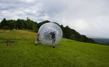 Sırt çantası ve insansız hava aracıyla çayırda şapkalı bir adam.