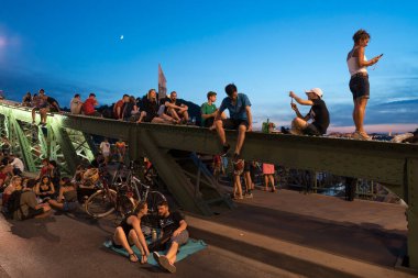 Budapeşte, Macaristan - 6 Temmuz 2019: Macar başkentinin en eski köprülerinden biri olan Liberty Köprüsü 'nde yaz gecesinin tadını çıkaran tanımlanamayan insanlar. Köprü hafta sonları ulaşıma kapatıldı.