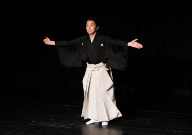 Japon adam karanlık sahnede oynuyor.