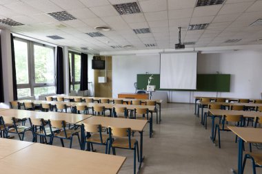 Modern bir kütüphanede sandalyeleri ve masaları olan okul sınıfı.