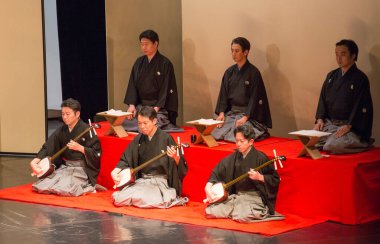 Kimliği belirsiz insanlar Japon tarzında tiyatro sahnelerinde oynuyorlar.