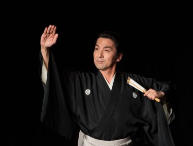 Japon adam karanlık sahnede oynuyor.