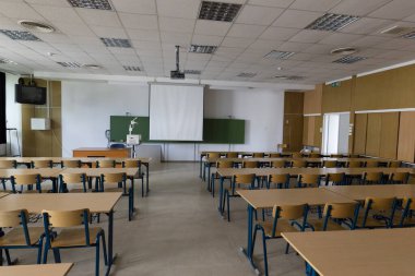 Modern bir kütüphanede sandalyeleri ve masaları olan okul sınıfı.