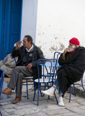 İki adam bankta oturuyor ve telefonda konuşuyor.