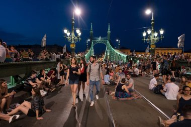 Budapeşte, Macaristan - 6 Temmuz 2019: Macar başkentinin en eski köprülerinden biri olan Liberty Köprüsü 'nde yaz gecesinin tadını çıkaran tanımlanamayan insanlar. Köprü hafta sonları ulaşıma kapatıldı. 