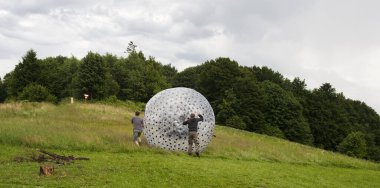 Dağ tepesinde büyük şeffaf topları olan adamlar.