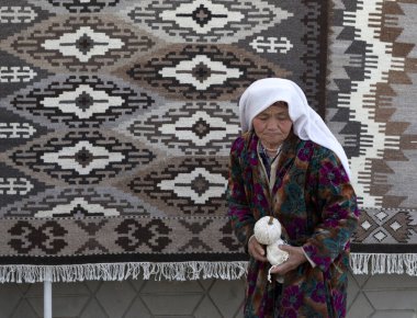 BÜKHARA, UZBEKISTAN - 21 Mart 2012 'de Özbekistan' ın Buhara kenti yakınlarında turist için poz veren geleneksel bulutlu kadın. Özbekistan 'ın genişletilmiş bir turizm sektörü için büyük potansiyeli var.