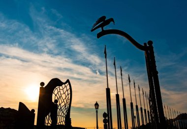 Gün batımında çitte kuş heykeli